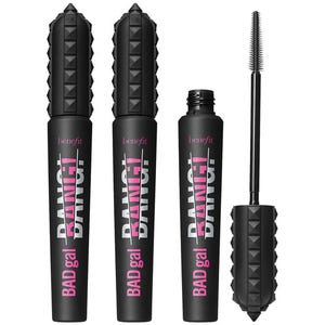 Three Benefit BADgal BANG! mascaras with spiked black tubes and pink lettering, featuring one open showing a slim brush for volumizing lashes.