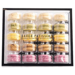 A box containing assorted French macarons from Savor Patisserie, featuring a variety of colors and flavors neatly arranged in a clear plastic case.