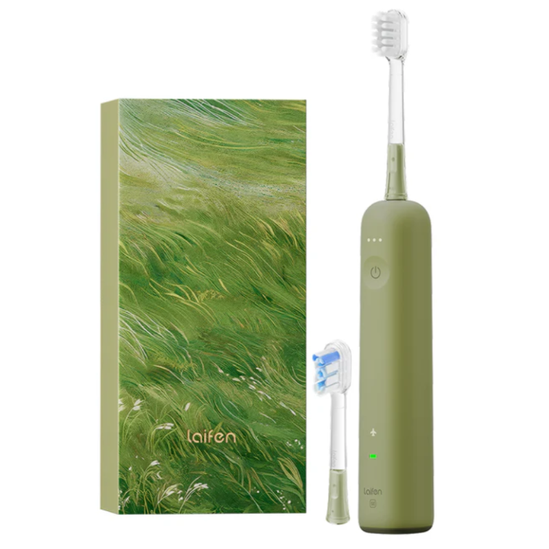 Green electric toothbrush set next to a box with a nature-inspired grass design, includes an extra brush head.