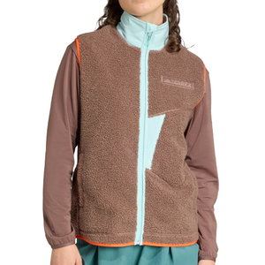 Brown fleece vest with a light blue zipper and asymmetrical design, featuring \“TERREX\“ branding. Worn over a light blue high-collar shirt and brown long-sleeve top.