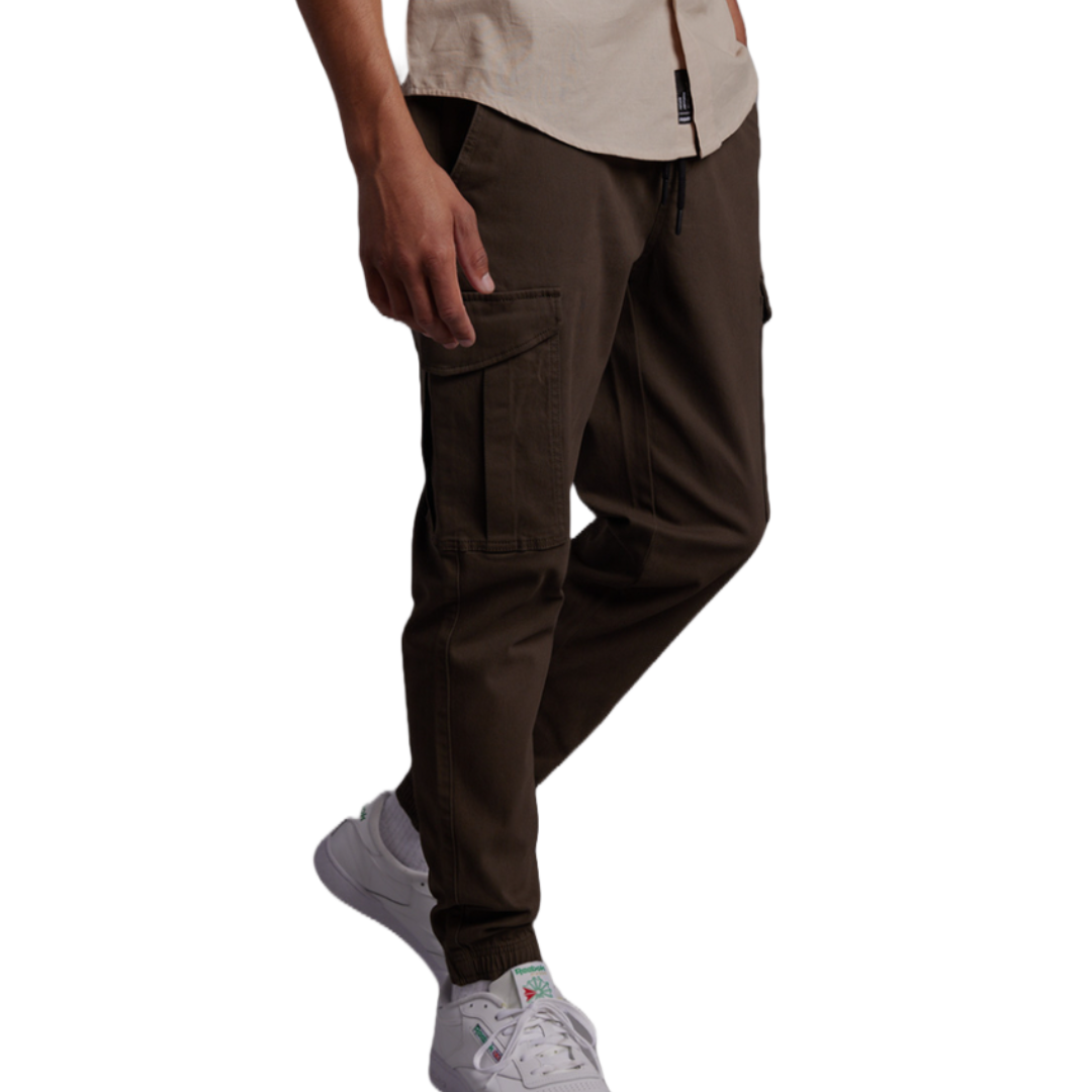 RSQ Men's Twill Cargo Jogger Pants are brown, featuring multiple cargo pockets and ankle cuffs for a tapered fit. Paired with white sneakers, they offer a casual and functional style.