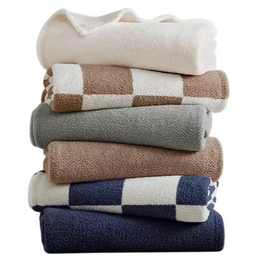 A stack of folded towels in various colors and patterns, including solid white, beige, gray, and blue, with some featuring checkered designs.