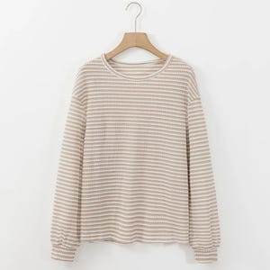 Striped long-sleeve sweater on a wooden hanger against a white background.
