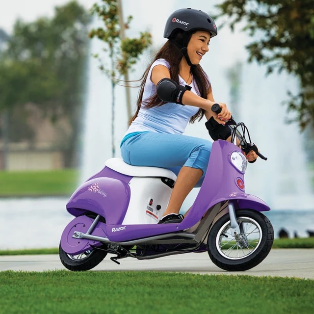 A person is riding a purple electric scooter with protective gear.