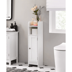 A slim white bathroom cabinet with a small door at the bottom and an open shelf above, holding a roll of toilet paper and decorative items like a vase with flowers and a candle. It's positioned on a patterned black and white floor next to a sink.