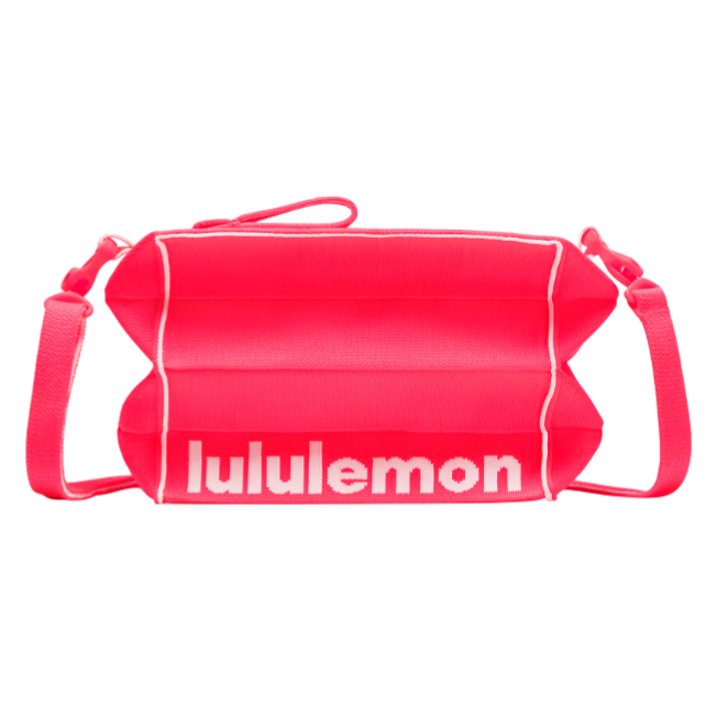 A pink crossbody bag with white piping, featuring the \“lululemon\“ logo in white text across the front.