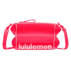 A pink crossbody bag with white piping, featuring the \“lululemon\“ logo in white text across the front.