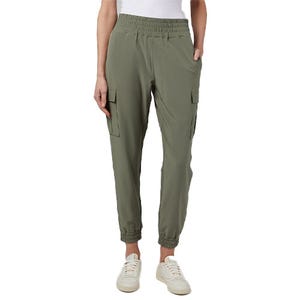 Women's stretch cargo joggers in olive green feature an elastic waistband, side pockets, and cargo-style pockets on the thighs. The joggers have a tapered fit with elastic cuffs, paired with white sneakers.