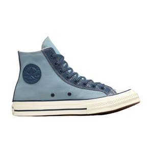 The Converse Chuck 70 Leather Overlays features a high-top design with blue canvas material and leather overlays, a signature star logo patch, and a cream midsole with blue stripe detailing.