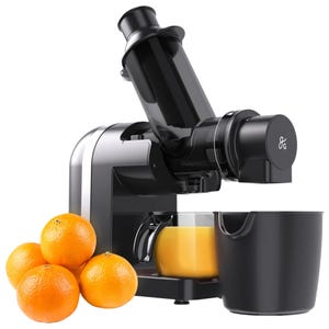 A black juicer with horizontal design sits next to a few oranges, processing them into a glass of orange juice, accompanied by a pulp waste container.