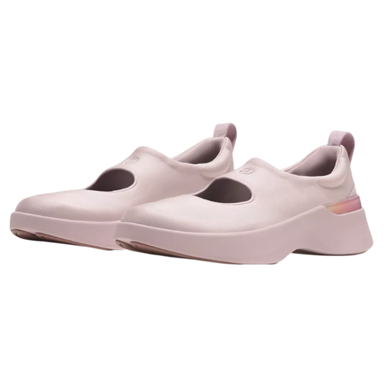 A pair of pink slip-on shoes with a wide strap and rounded design, featuring a low platform sole and a loop at the heel for easy wear.