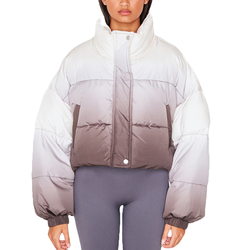 A cropped puffer coat with a monochrome ombre design transitioning from white at the shoulders to gray and dark brown at the waist, featuring a high collar and snap-button closure.
