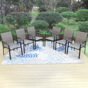 Six metal-framed patio chairs with mesh backs and seats are arranged on a large outdoor rug featuring a blue and beige leafy pattern, set on a wooden deck with greenery in the background.