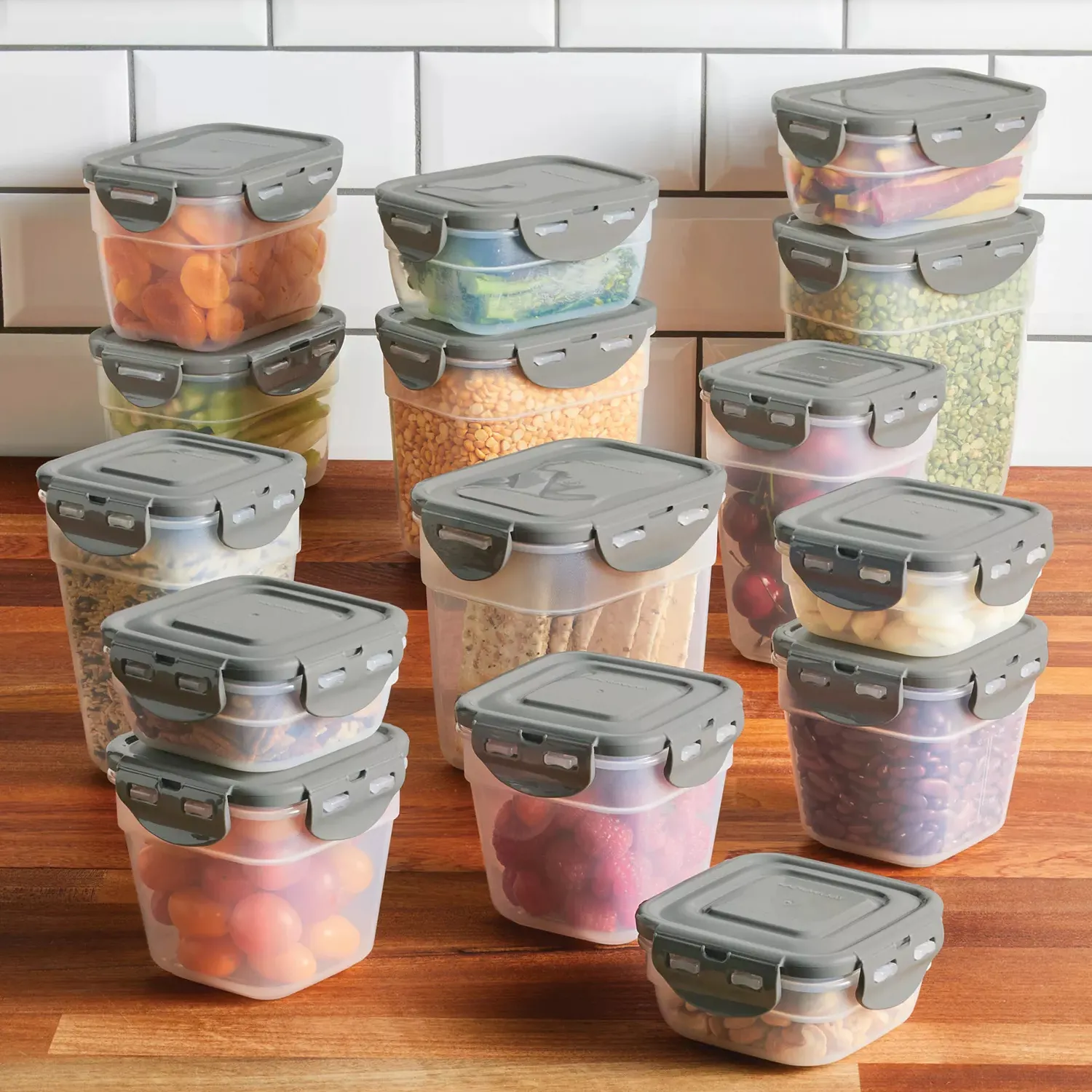 A collection of transparent, rectangular food storage containers with gray lids, featuring locking mechanisms, filled with various dried foods, fruits, and vegetables.