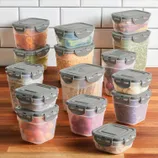 A collection of transparent, rectangular food storage containers with gray lids, featuring locking mechanisms, filled with various dried foods, fruits, and vegetables.