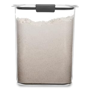 A clear rectangular container with a black handle on the lid, filled with a white powdery substance, possibly flour or sugar.