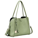 A light green handbag made of textured material with long shoulder straps and metal hardware, including a decorative tassel and adjustable strap.