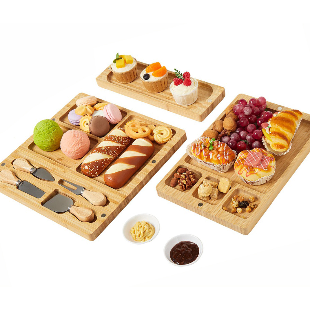 Wooden serving trays with sections displaying a variety of pastries, macarons, cheese knives, nuts, fruits, and dips.