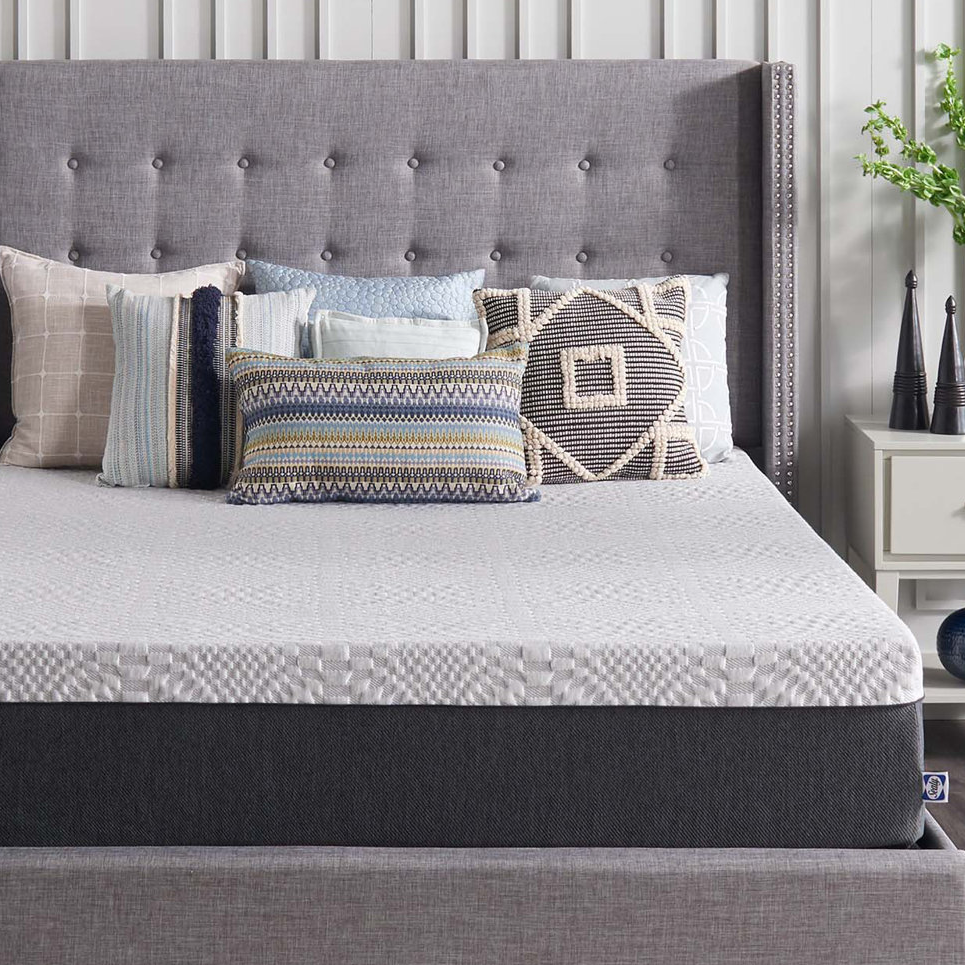 A neatly arranged bed with a tufted headboard, patterned pillows, and a textured comforter.