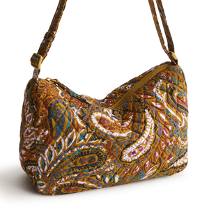 A quilted paisley-patterned shoulder bag with an adjustable strap and zipper closure in warm colors like brown, gold, and blue.