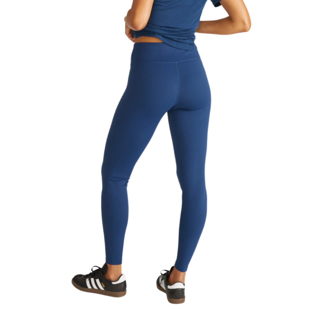 A person is wearing blue high-waisted leggings paired with black Adidas sneakers featuring white stripes.