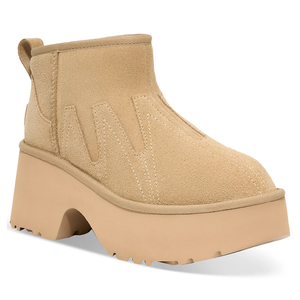 A tan suede platform ankle boot with zigzag stitching, featuring a chunky sole and a pull tab at the back.