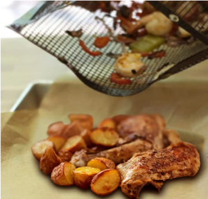 Grilled chicken drumsticks and roasted potatoes on parchment paper, with vegetables being emptied from a woven bag.