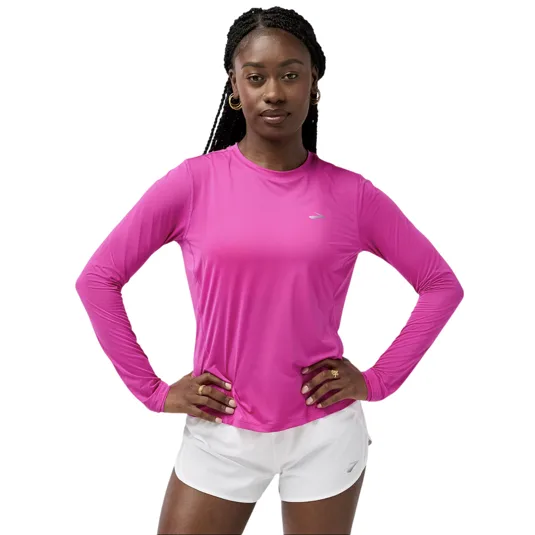 A person wearing a pink long-sleeve athletic top with a small logo, paired with white shorts.