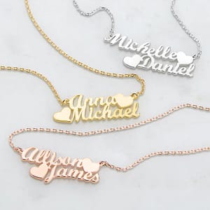Sterling Silver Couples Name Necklace showcases two interlocked names, \“Michelle\“ and \“Daniel,\“ in elegant script with a small heart accent between them, designed on a delicate silver chain.