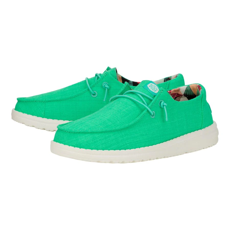 Bright green Hey Dude Wendy shoes with white soles and colorful interior lining, featuring a low-top, lace-up design.