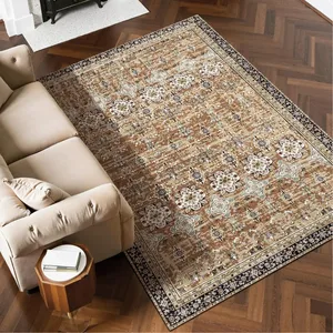 A beige and cream Persian-style area rug with floral and geometric patterns is placed on a herringbone hardwood floor beside a light beige sofa and a small wooden side table.