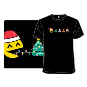 The black Pac-mas tee features a playful design with a yellow character wearing a Santa hat, interacting with a Christmas tree and festive icons, including a snowman, gingerbread cookie, and Santa Claus.
