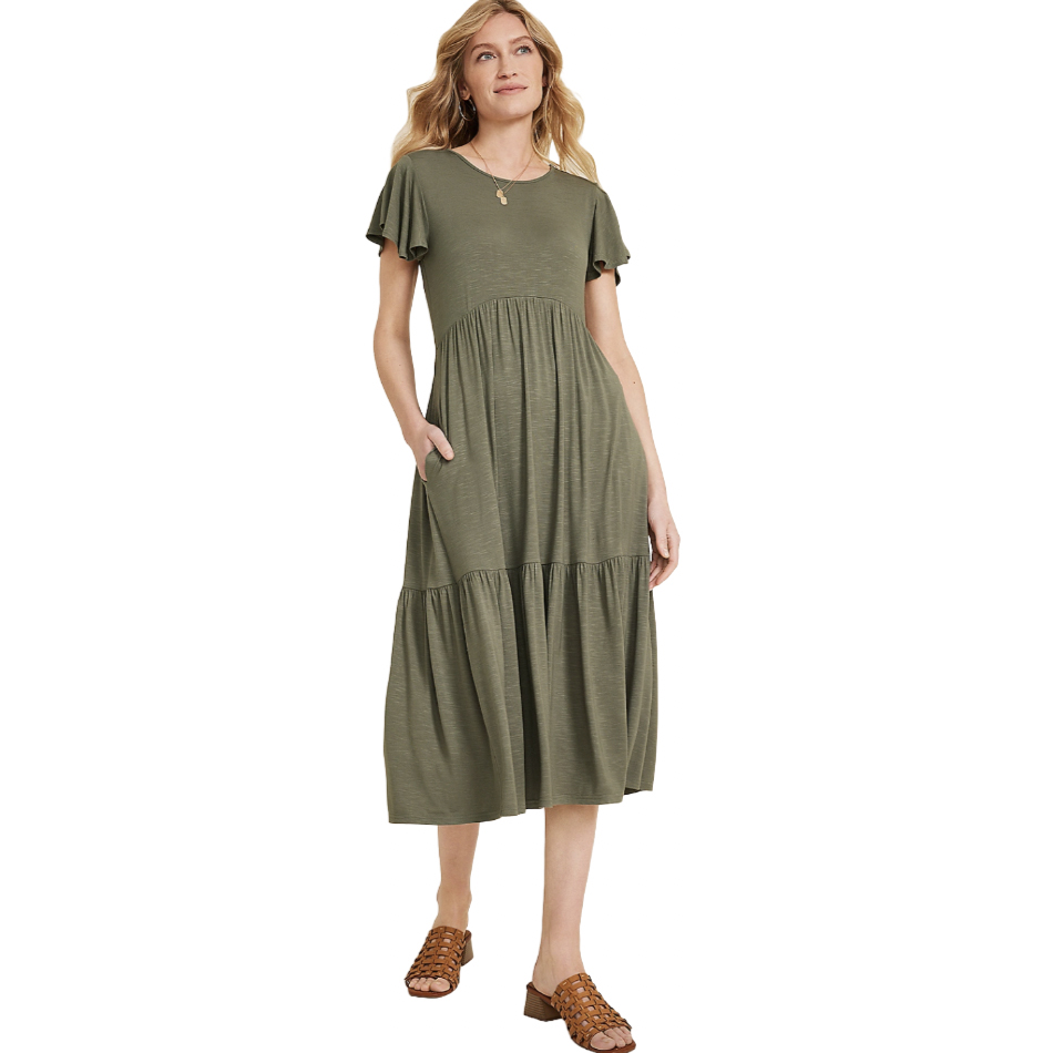 A woman is wearing an olive green, short-sleeve, tiered midi dress with a relaxed fit and pockets, paired with brown woven open-toe sandals.