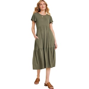 A woman is wearing an olive green, short-sleeve, tiered midi dress with a relaxed fit and pockets, paired with brown woven open-toe sandals.