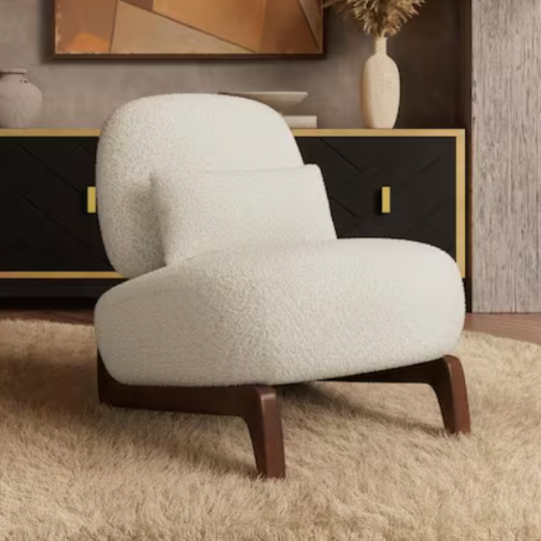 A white, cushioned armchair with wooden legs sits on a beige rug in front of a black and gold sideboard adorned with vases and abstract wall art.