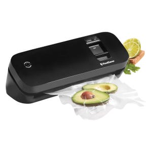 A black FoodSaver vacuum sealer is pictured sealing a bag with avocado slices. The device features a simple control panel with options for seal and vacuum, and is accompanied by examples of vacuum-sealed food items like salmon and lime slices.