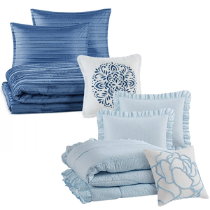 Bedding set with blue and white pillows and quilts in varied textures and patterns.