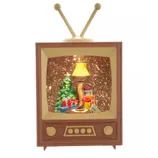 A vintage-style TV decoration with a Christmas scene inside, featuring a tree, gifts, and a leg-shaped lamp with fishnet stockings.