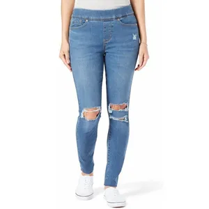High-waisted blue distressed skinny jeans with ripped knees, styled with a tucked-in white top and white sneakers.