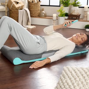 A woman lying on a yoga mat, holding a smartphone.