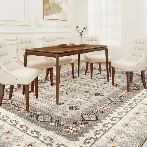 A dining room scene featuring a set of cushioned chairs with wooden legs surrounding a rectangular wooden table, all placed on a patterned area rug.