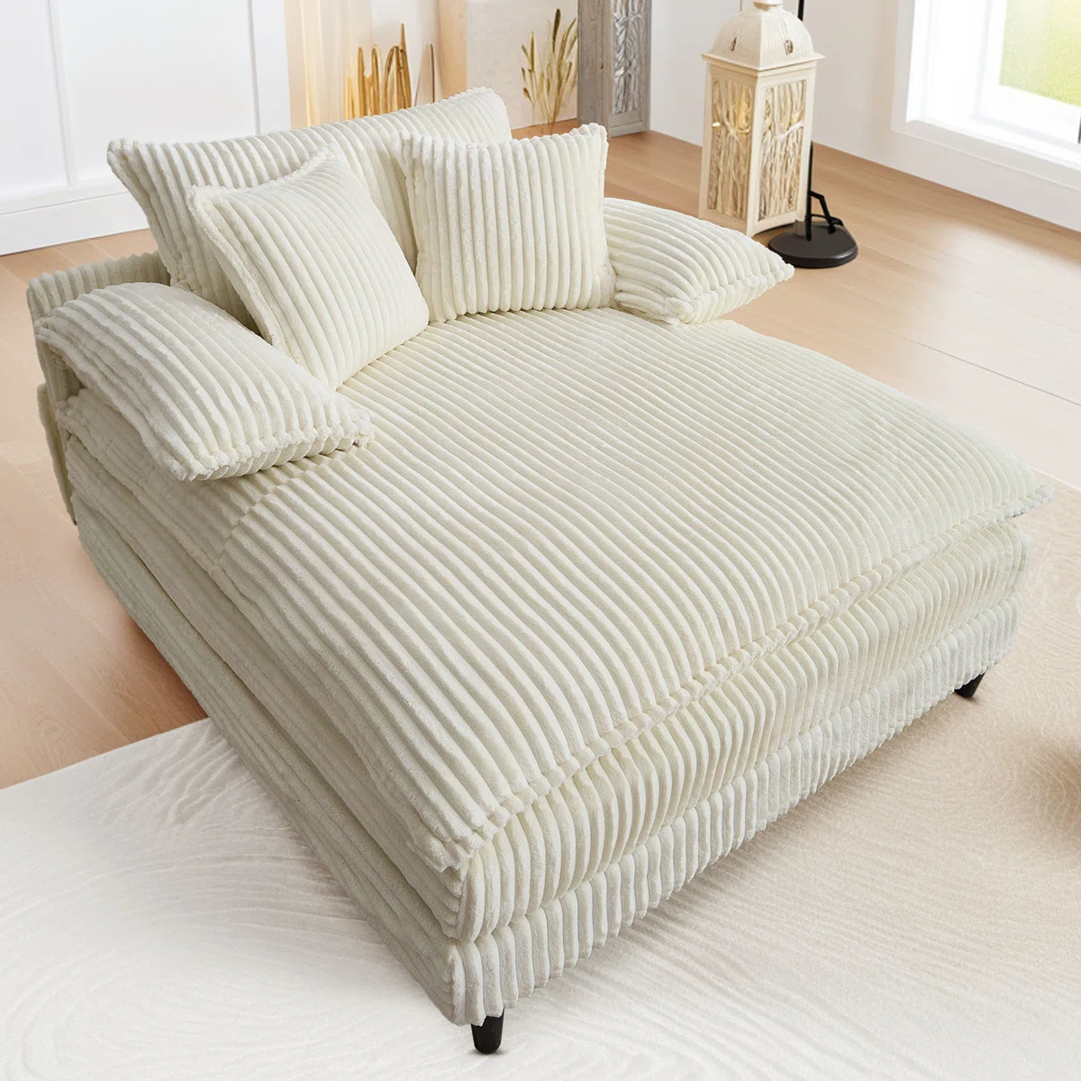 Cream-colored corduroy sectional lounge chair with multiple cushions, set in a cozy room with light wood floors and natural decor accents.