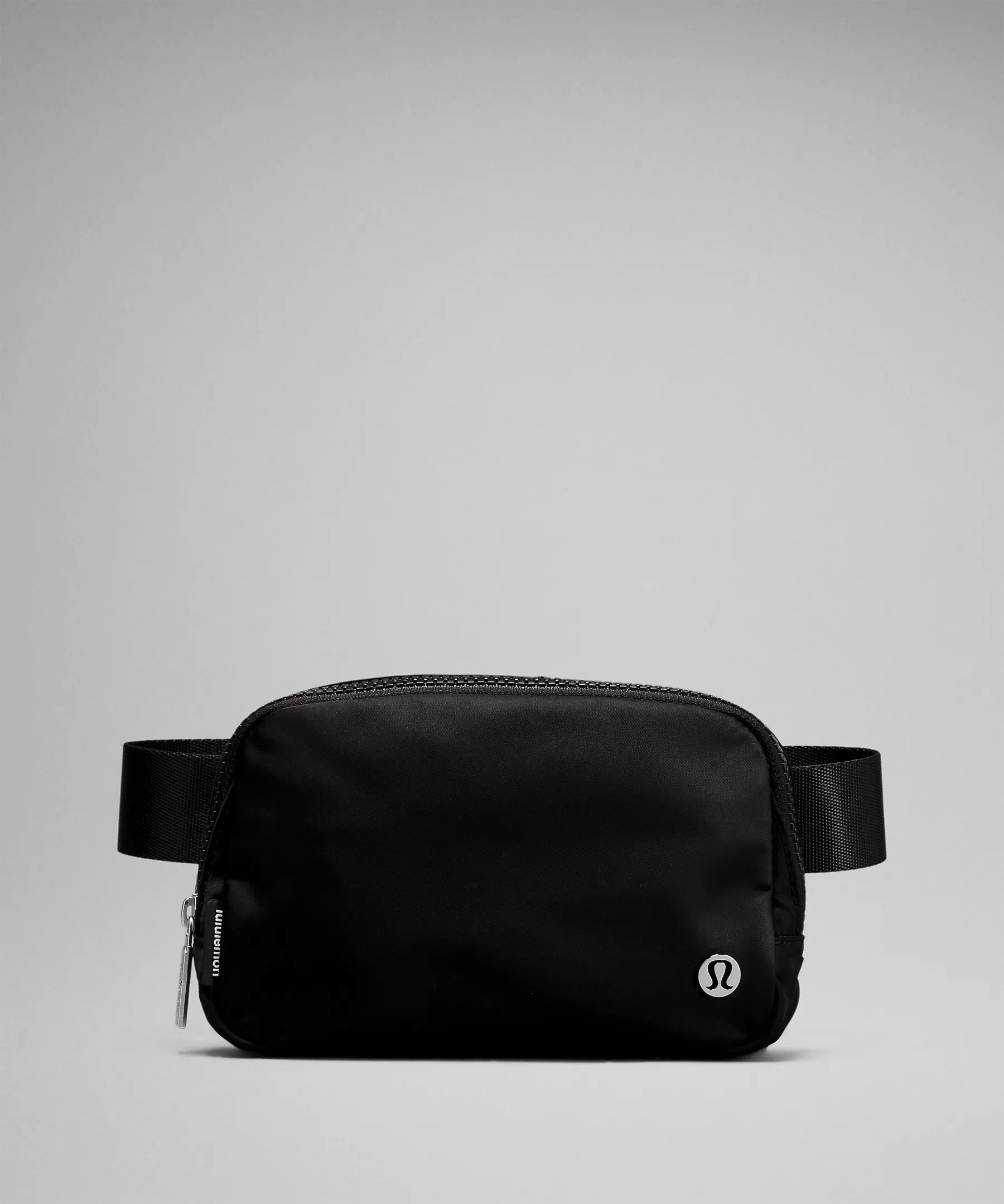 A black belt bag with a visible logo and a zipper closure on a grey background.