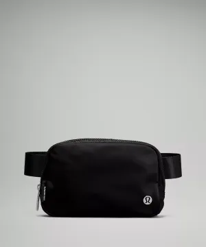 A black belt bag with a visible logo and a zipper closure on a grey background.