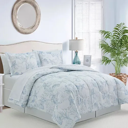 8-piece set includes a comforter with light blue and white coastal print, matching shams, a decorative pillow, and a bed skirt. The design features subtle sea-themed patterns, complementing a calm bedroom style. Includes lamp and framed picture accents.