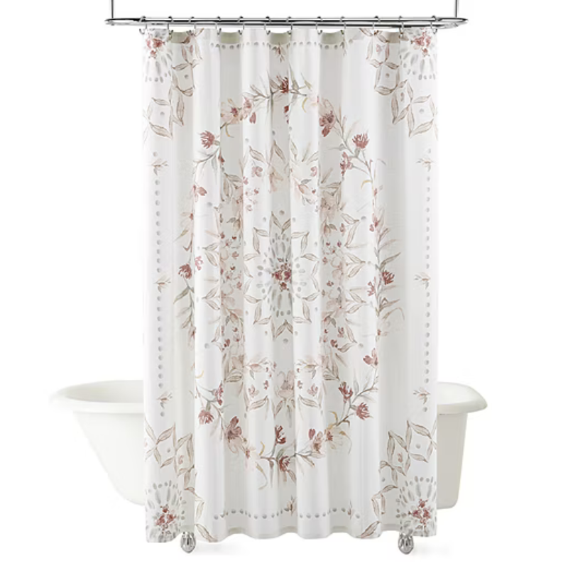 White shower curtain with a floral mandala design in soft pink and beige hues. Hanging on a metal rod above a freestanding bathtub.