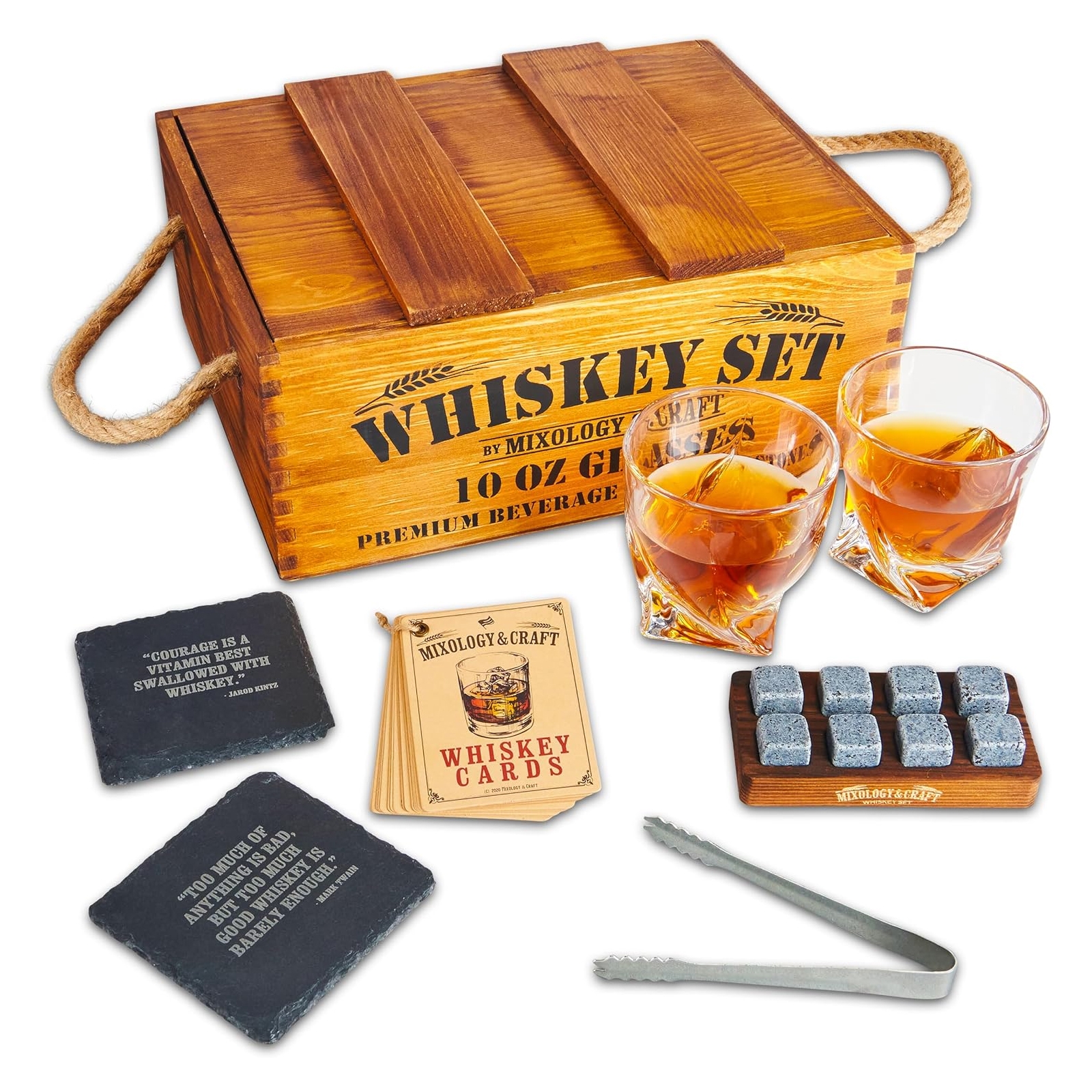 A wooden box labeled \“Whiskey Set\“ includes two 10 oz glasses, whiskey stones with a wooden tray, metal tongs, slate coasters with quotes, and a set of Mixology & Craft whiskey cards.