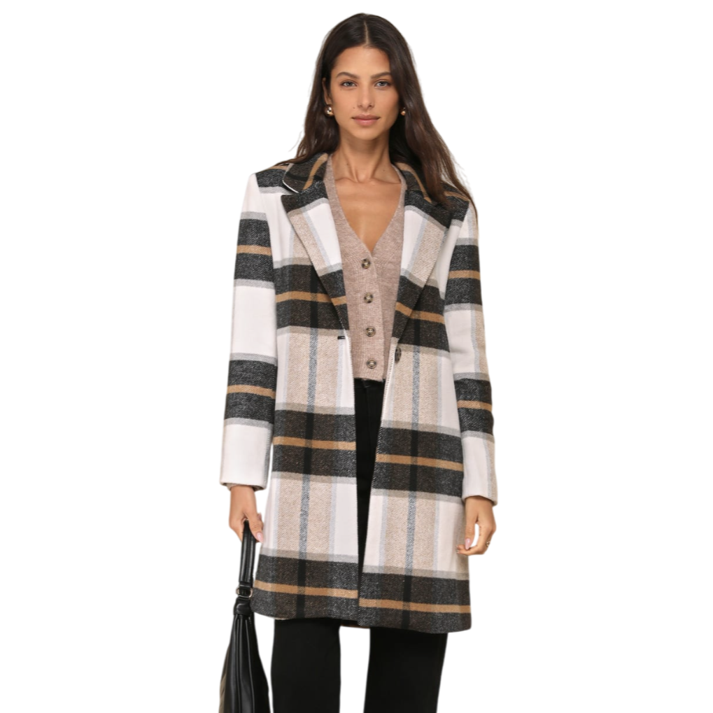 A woman is wearing a plaid coat over a buttoned cardigan, paired with black pants and black flat shoes. She carries a black handbag.