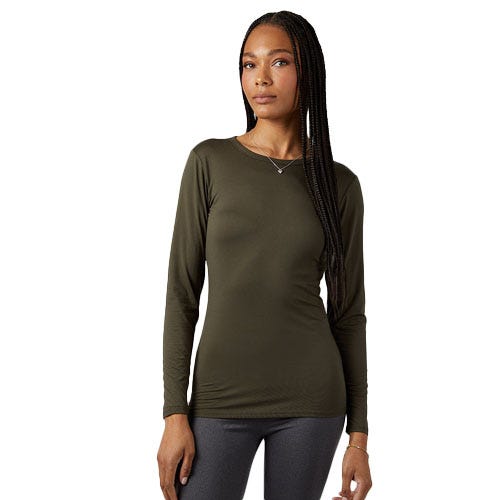 A woman is wearing a long-sleeve, dark olive green top and gray leggings. She has long, braided hair and is standing in a relaxed pose.