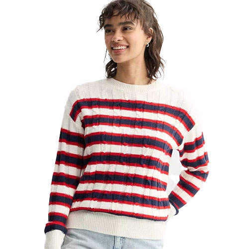 A person wears a striped sweater with red, white, and blue horizontal lines and light-colored jeans.